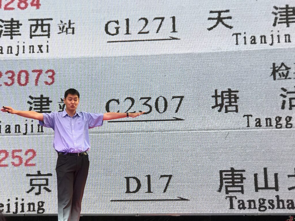An image of David Feng onstage behind a picture of Chinese railway tickets